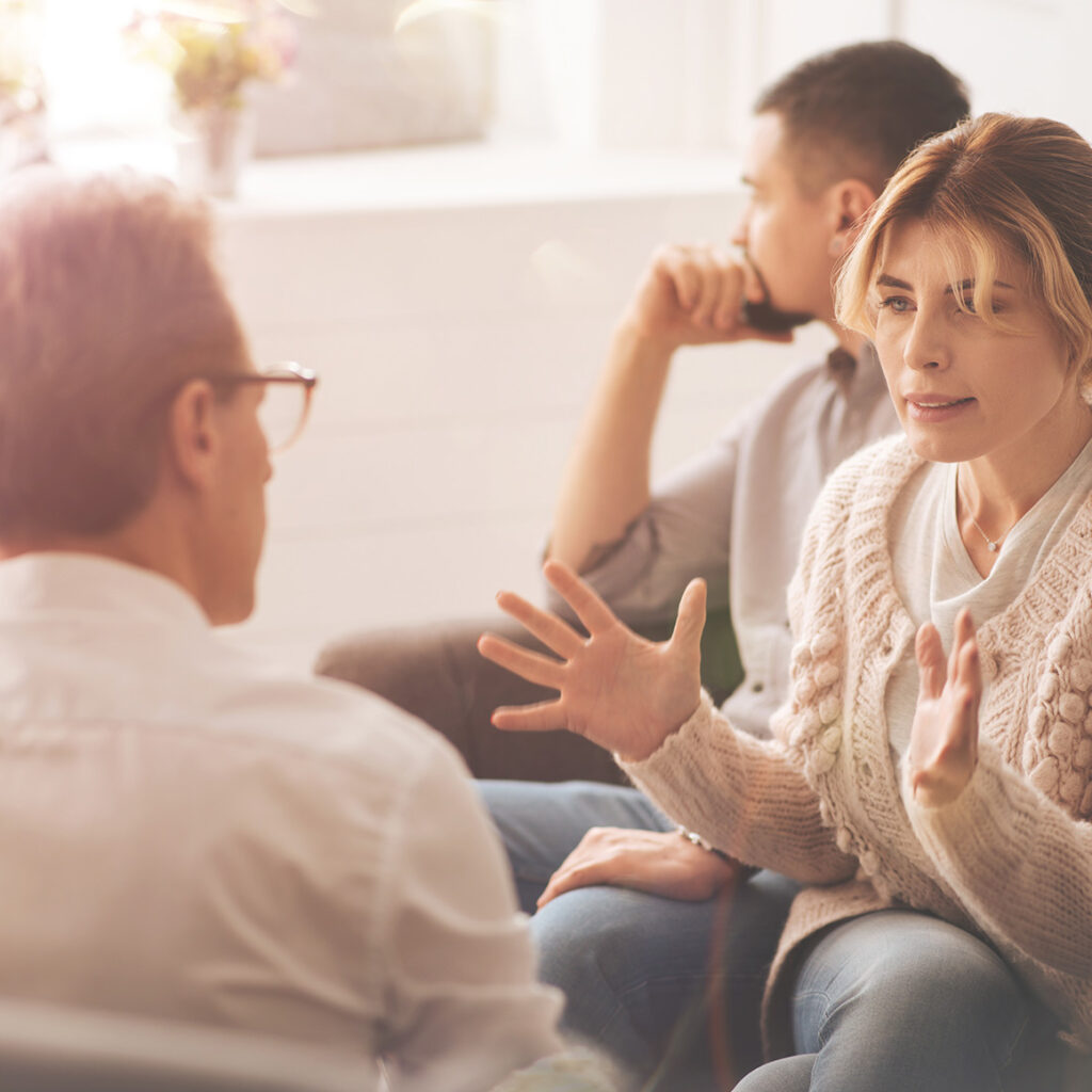 a woman speaking and using her hands while talking to a man sitting across from her