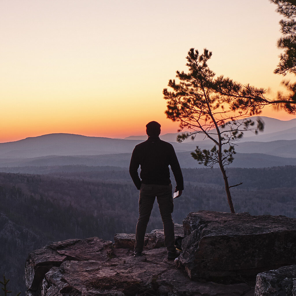 an image of a man at the top of a mountain looking pensively into the distance